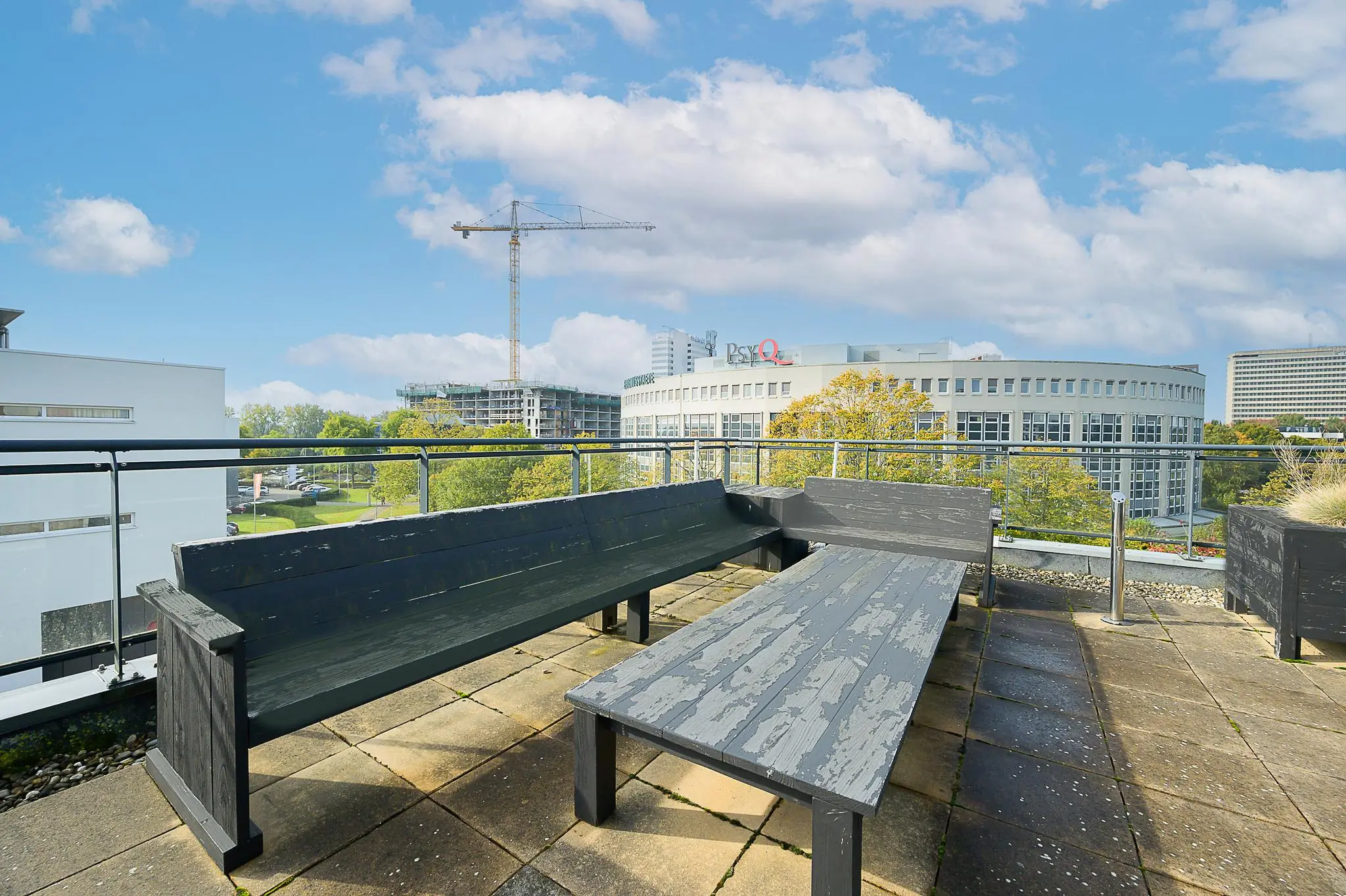 Dakterras met houten zitbanken en uitzicht op het PsyQ-gebouw aan de K.P. van der Mandelelaan.